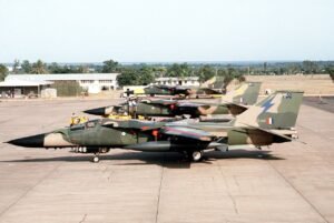 Three camouflaged RAAF F-111C aircraft parked together on an Australian air base flight line